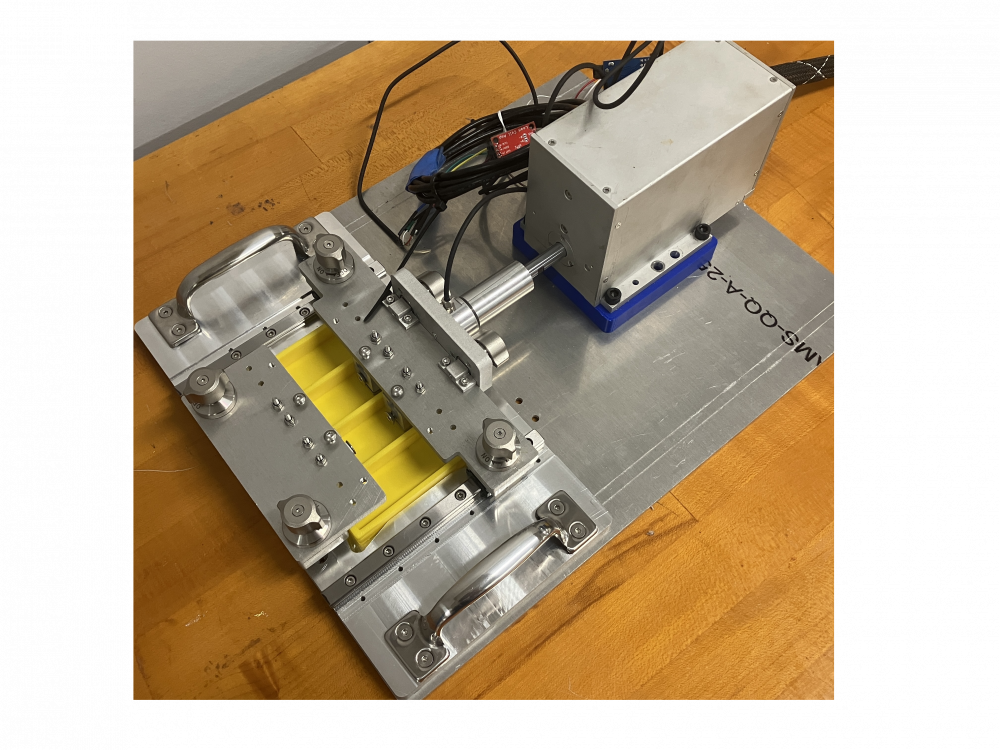 A image of a cell stretching machine. The machine has a sliding gantry with clamps sticking into a petri dish from above.
