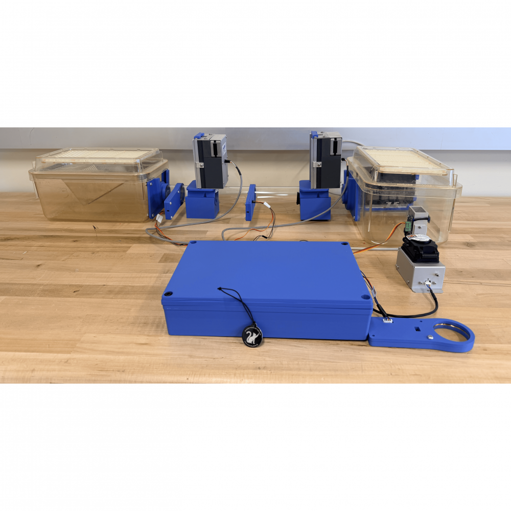Photograph of the assembled mouse training system, with a clear acrylic tube and RFID gate modules connecting the home cage to the touchscreen trainer.