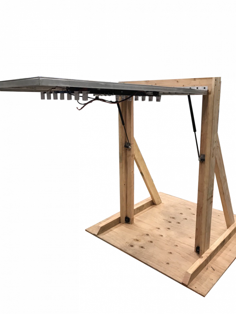 The final prototype of the door component for the Sealed Portal for Commercial Sterilization Machine. The three main components shown are the door, the piano hinge, and the gas struts. The components are assembled onto a wooden frame.